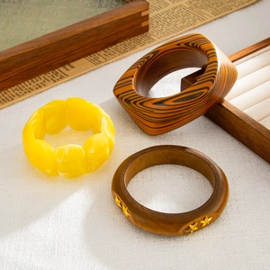 Dettaglio di bracciali in resina e legno con trame vintage e accenti di stelle
