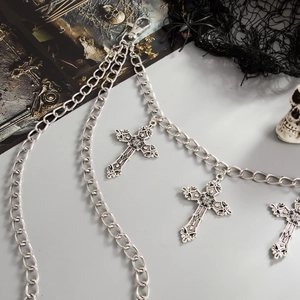 Gothic silver metal thigh chain with triple cross pendants and clasp on dark background