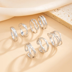Detailed set of 7 silver irregular geometric stackable rings on warm beige background
