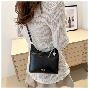 Sac à bandoulière noir avec nœud en perles et breloque cœur porté par un mannequin