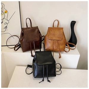 Dettaglio di zaini minimalisti in ecopelle nei colori nero, marrone scuro e marrone chiaro