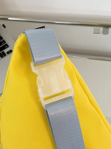 Detailaufnahme der gelben Canvas-Umhängetasche mit blauem Gurt und Steckverschluss