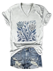 Vista piatta di una maglietta bianca con scollo a V, stampa floreale blu e shorts in denim