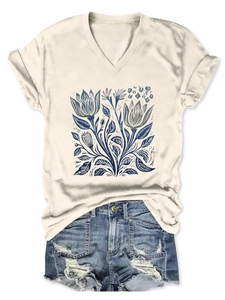Dettaglio flat lay di una t-shirt bianca con scollo a V e fiori e pantaloncini di jeans