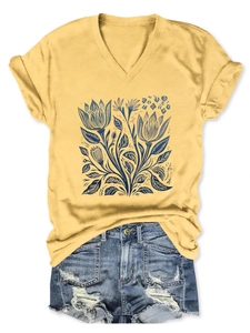 Dettaglio della stampa floreale blu su t-shirt gialla scollo a V e shorts in denim