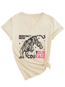 Dettaglio della t-shirt beige con scollo a V, grafica a tigre, slogan e nodo decorativo frontale