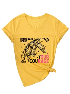 Dettaglio maglietta gialla con scollo a V, stampa a tigre e testo Democracy Needs Your Courage