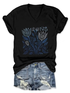 Dettaglio della stampa floreale blu vintage su t-shirt nera con scollo a V da donna