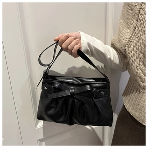 Dettaglio della borsa tote in ecopelle nera con pieghe, fiocco e borchie a stella