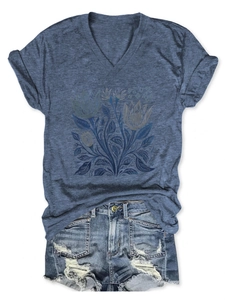 Dettaglio della maglietta blu con scollo a V floreale e pantaloncini in denim usurati