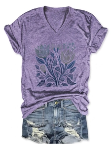 Dettaglio della stampa floreale su maglietta viola scollo a V e pantaloncini denim