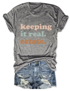 Dettaglio della t-shirt grigia con stampa colorata e pantaloncini di jeans strappati