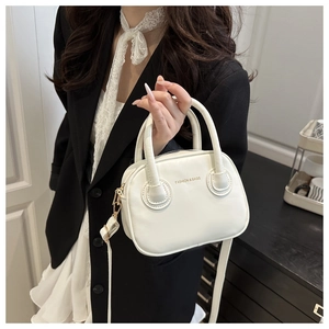 Detailed close-up of white leather Boston bag with gold FASHION logo and elegant hardware
