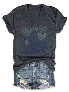 Dettaglio della stampa floreale blu su maglietta grigia a scollo a V e denim shorts