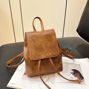 Zaino retrò in ecopelle marrone con chiusura a patta su sedia con riviste moda