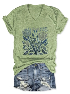 Dettaglio di t-shirt verde con scollo a V, stampa floreale e shorts in denim
