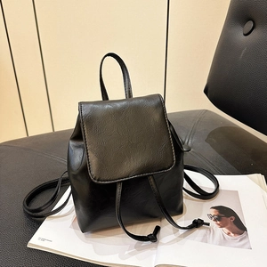 Zaino nero minimalista in ecopelle con trama martellata su una sedia elegante