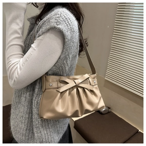Dettaglio della borsa beige con fiocco e rivetti a stella su pelle a pieghe