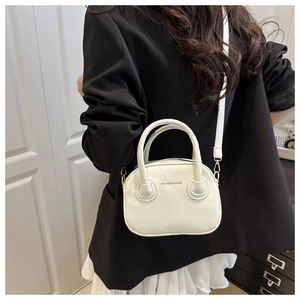 Detailed side view of a white minimalist handbag worn by a model in a black blazer
