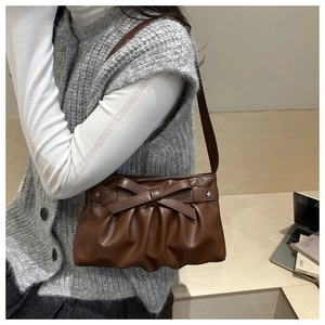 Dettaglio borsa a spalla in pelle marrone con fiocco e rivetti a stella argentati decorativi