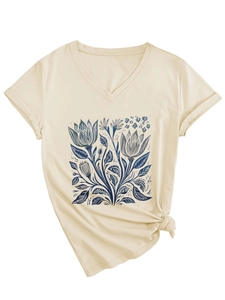 Dettaglio di una maglietta beige con scollo a V, stampa floreale blu e nodo laterale