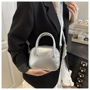 Detail of silver metallic mini handbag with Fashion & Bags text on a black blazer outfit