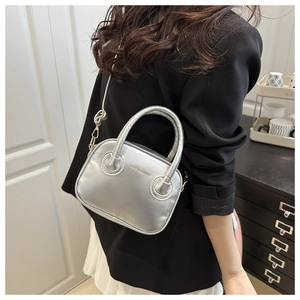 Close-up of a silver mini handbag with metallic leather and chain strap on a model