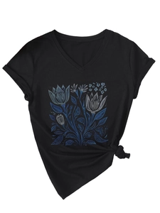 Dettaglio di una t-shirt nera con scollo a V, stampa floreale blu e nodo laterale alla moda