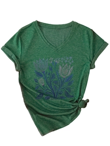 Dettaglio maglietta verde scollo a V con stampa floreale blu e dettaglio nodo frontale