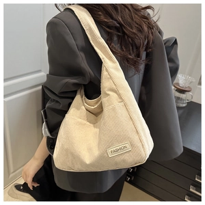 Detailed texture of beige corduroy tote bag featuring a stitched fashion label on front