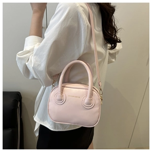 Detail view of light pink matte PU leather small square bag worn over the shoulder