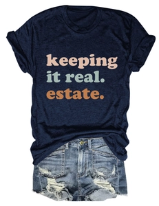 Dettaglio della t-shirt blu scuro con stampa keeping it real estate e pantaloncini denim