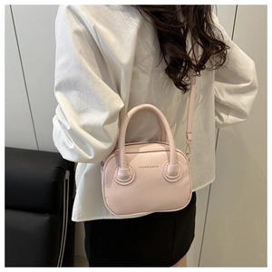 Model view of the pink round leather crossbody bag showing size and styling on shoulder