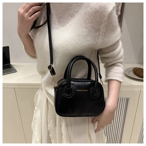Close-up of black leather mini handbag with gold lettering and slim shoulder strap