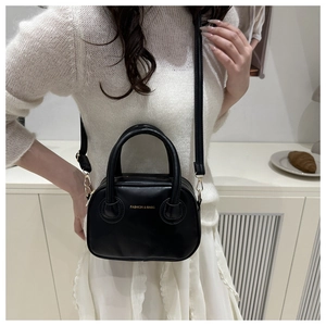 Détail du sac à main noir en similicuir avec lettrage doré et anses rondes
