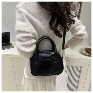 Détail d'un élégant sac à main en cuir noir avec ferrures dorées dans un café