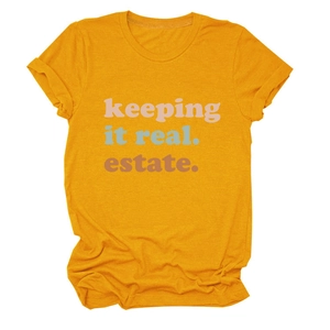 Dettaglio di una maglietta in cotone giallo zenzero con stampa colorata 'keeping it real estate'