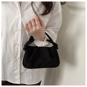 Dettaglio borsa a mano in pelle scamosciata nera con manico a nodo e texture minimalista