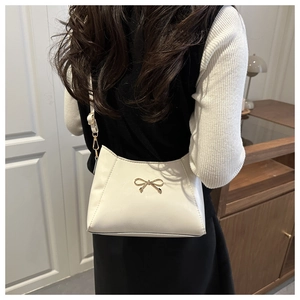 Detailed back view of a white PU leather shoulder bag with a gold bow buckle worn by a model