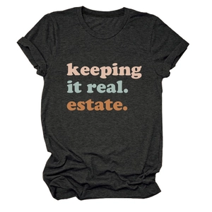 Dettaglio della stampa testuale 'keeping it real estate' su t-shirt grigio scuro