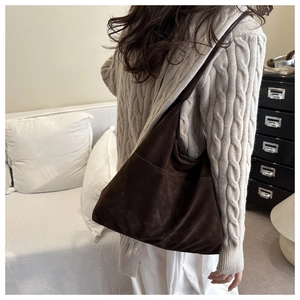 Détail d'un grand sac cabas en daim marron foncé avec large bandoulière sur l'épaule