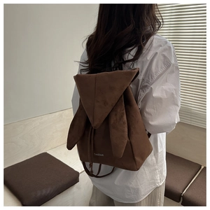 Detail of dark brown suede backpack featuring long rabbit ears and drawstring closure