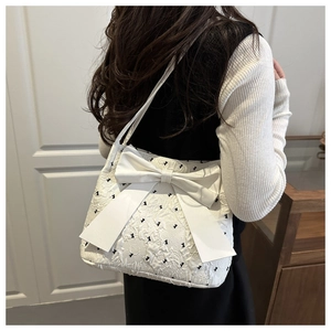 Detail of white seersucker tote bag featuring black bow patterns and large 3D bow accent
