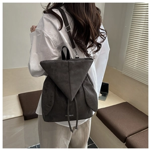 Detailed view of the dark gray suede backpack with adjustable metal buckles and drawstrings