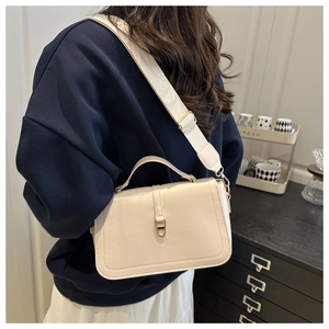 Détail du sac bandoulière blanc crème avec boucle dorée et large bandoulière en tissu