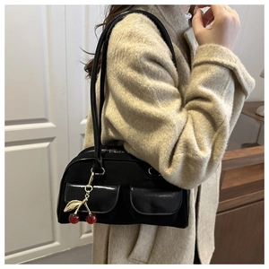 Detail der schwarzen Baguette-Tasche mit Lack-Klapptaschen und Kirsch-Anhänger