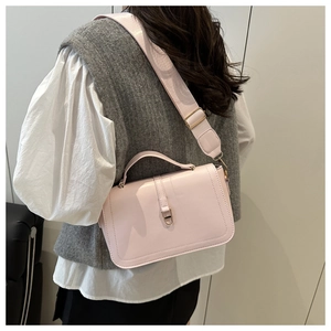 Détail d'un petit sac carré rose clair avec bandoulière large porté par un mannequin