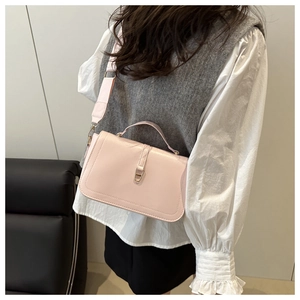 Detail van lichtroze lederen crossbodytas met gouden metalen gesp en brede schouderriem