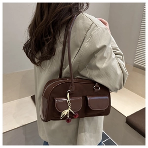 Detail of vintage brown baguette bag with dual pockets and metal cherry charm