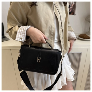 Detail of black leather underarm bag with gold metal buckle and wide shoulder strap